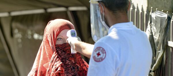 Zdravstveni radnik meri temperaturu ženi pre nego što joj odobri pristup spomen-groblju u Potočarima, blizu Srebrenice, Bosna, subota, 11. jul 2020. Zdravstveni radnik meri temperaturu ženi pre nego što joj odobri pristup spomen-groblju u Potočarima, blizu Srebrenice, Bosna, subota, 11. jul 2020. - Sputnik Srbija