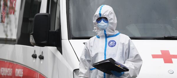 Лекар у заштитном оделу испред возила хитне помоћи Лекар у заштитном оделу испред возила хитне помоћи - Sputnik Србија