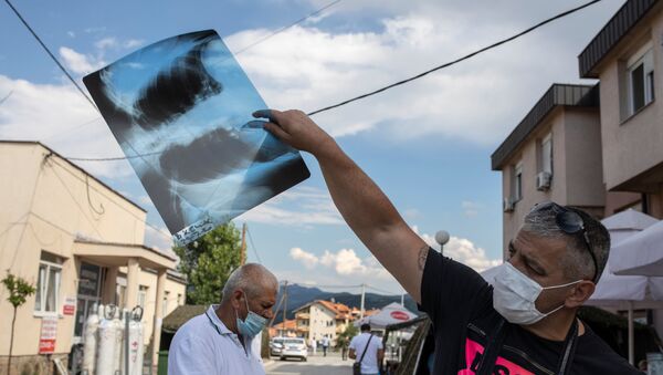 Човек позитиван на корону показује свој снимак плућа испред ковид болнице у Новом Пазару - Sputnik Србија