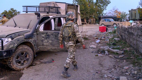 Azerbejdžanski vojnik prolazi pored uništenog vojnog vozila u gradu Džabrail koji su zauzele azerbejdžanske snage tokom sukoba u Nagorno-Karabahu - Sputnik Srbija