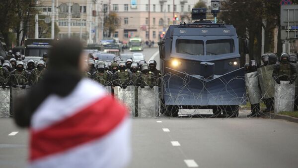 Демонстрант са опозиционом заставом испред кордона полиције на протесту у Минску - Sputnik Србија