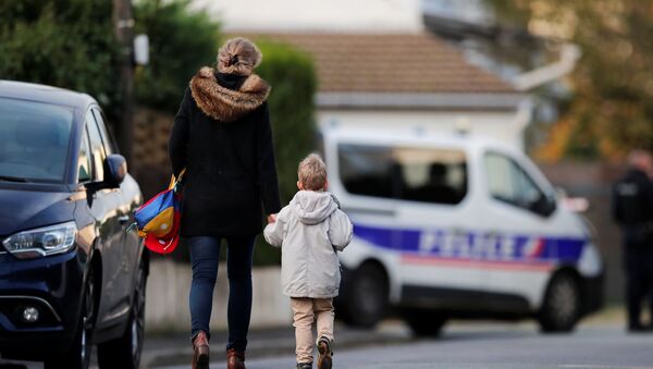 Жена држи дете за руку на путу до школе у околини колеџа где је Самуел Пати, учитељ француског, обезглављен на улицама париског предграђа  - Sputnik Србија