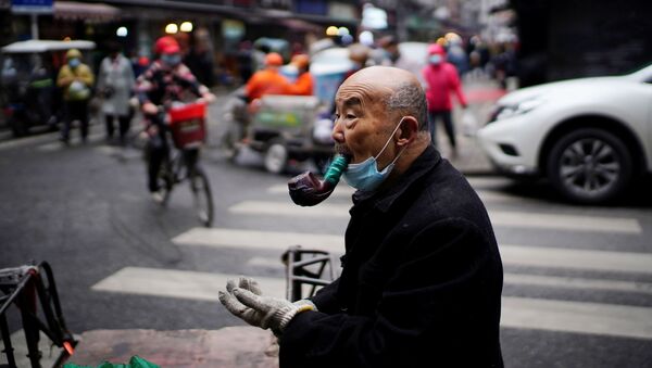 Гонг Синхуа, 76, са заштитном маском, пуши лулу на уличној пијаци скоро годину дана након избијања пандемије у Вухану, провинција Хубеј, Кина, 7. децембра 2020. године. - Sputnik Србија