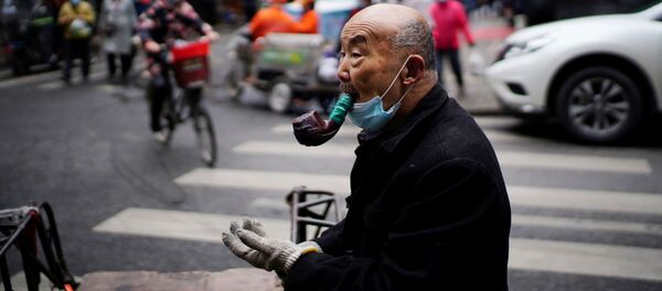 Gong Sinhua, 76, sa zaštitnom maskom, puši lulu na uličnoj pijaci skoro godinu dana nakon izbijanja pandemije u Vuhanu, provincija Hubej, Kina, 7. decembra 2020. godine. - Sputnik Srbija