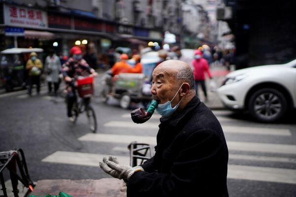Гонг Синхуа, 76, са заштитном маском, пуши лулу на уличној пијаци скоро годину дана након избијања пандемије у Вухану, провинција Хубеј, Кина, 7. децембра 2020. године. - Sputnik Србија