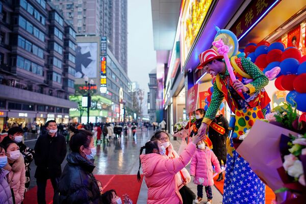 Кловн се поздравља са људима током промоција у главној шопинг зони  годину дана након избијања пандемије у месту Вухан, провинција Хубеј, Кина, 6. децембра 2020. - Sputnik Србија