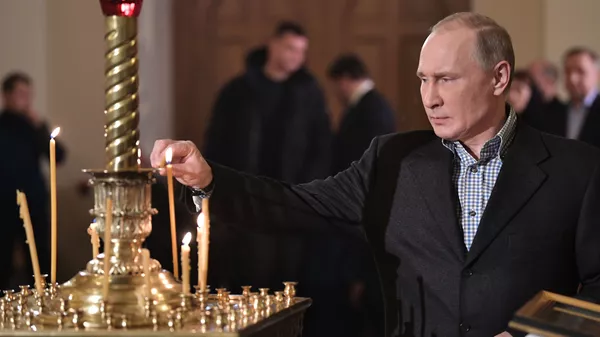 Председник Русије Владимир Путин пали свећу током божићне литургије у цркви Светог Симеона и Ане у Санкт Петербургу - Sputnik Србија