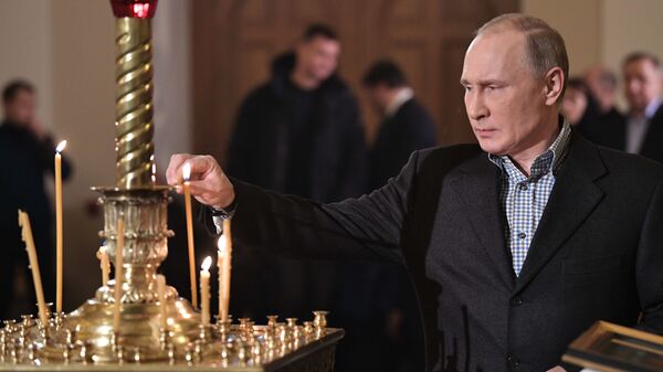 Predsednik Rusije Vladimir Putin pali sveću tokom božićne liturgije u crkvi Svetog Simeona i Ane u Sankt Peterburgu - Sputnik Srbija