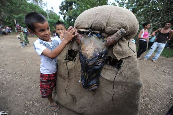 Dečak se igra sa učesnikom festivala „Feast of the Devils“ („Đavolja gozba“) u kostimu bika u Kostariki - Sputnik Srbija