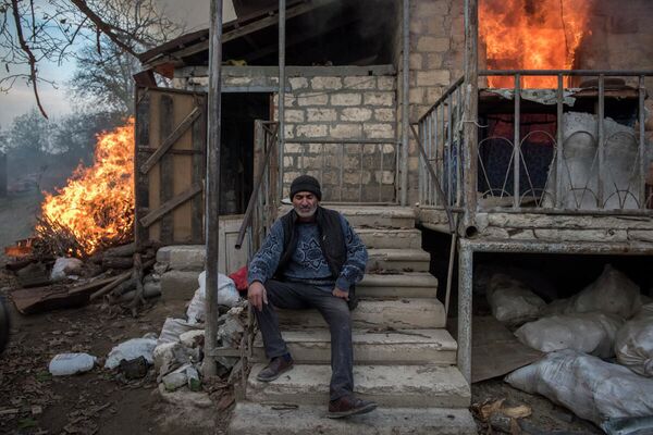  Areg sedi ispred zapaljene kuće u selu Karegah. Jedan broj stanovnika je zapalio svoje domove, pre nego što će se odseliti.  - Sputnik Srbija