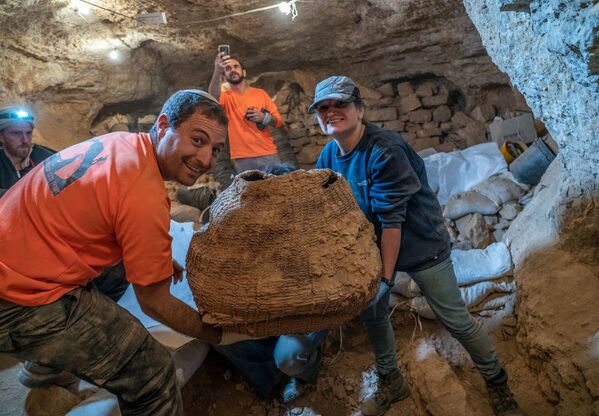 Izraelski arheolozi sa drevnom korpom pronađenom u pećini Murabat u Judejskoj pustinji nedaleko od Mrtvog mora. - Sputnik Srbija