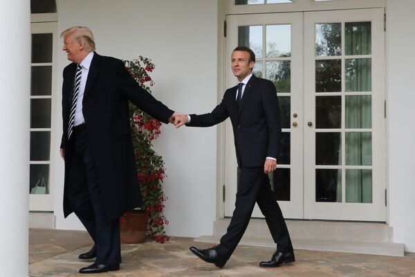 Francuski predsednik Emanuel Makron i bivši američki lider Donald Tramp šetaju ispod kolonada Bele kuće 2018. godine, držeći se za ruke  - Sputnik Srbija