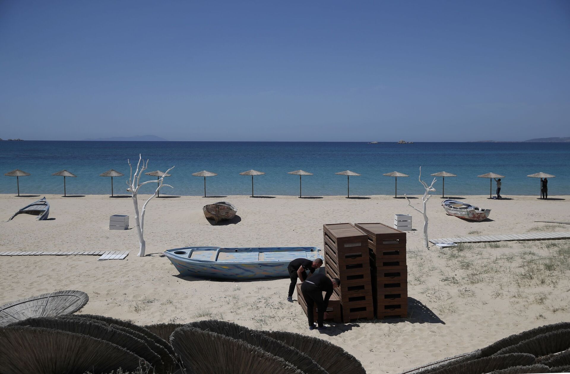 Radnici uređuju ležaljke i postavljaju suncobrane na plaži Plaka na egejskom ostrvu Naksos - Sputnik Srbija, 1920, 13.07.2021