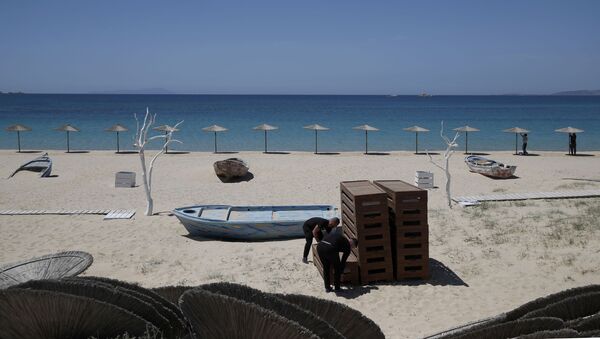 Радници уређују лежаљке и постављају сунцобране на плажи Плака на егејском острву Наксос - Sputnik Србија