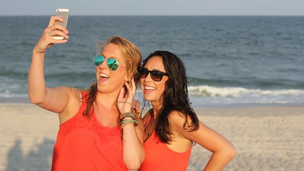 Devojke sa mobilnim telefonom na plaži - Sputnik Srbija