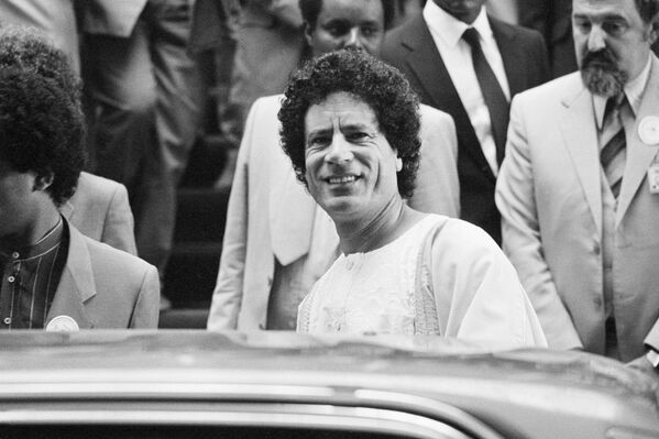 Либијски лидер Муамер ел Гадафи, осмехује се фотографима док напушта Афричку дворану током другог дана састанка Комитета на 19. самиту Организације афричког јединства у Адис Абеби, 7. јуна 1983. године. - Sputnik Србија