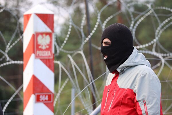 Слика снимљена 8. новембра 2021. приказује мигранта на белоруско-пољској граници у региону Гродно. Пољска је 8. новембра саопштила да се стотине миграната у Белорусији спуштају на њену границу са циљем да се на силу пробију у чланицу ЕУ,  што је НАТО оценио као намерну тактику Минска. - Sputnik Србија