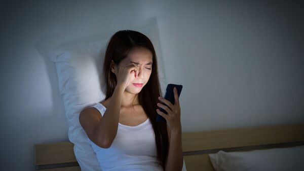 Dziewczyna z telefonem komórkowym w ręce w łóżku - Sputnik Srbija