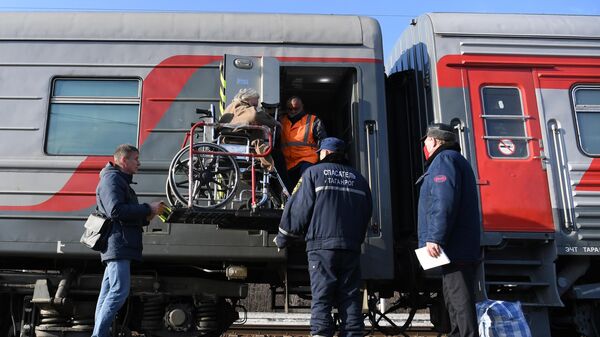 Pripadnici Ruskih železnica i Ministarstva za vanredne situacije Rusije pomažu izbeglicama iz Donbasa da se ukrcaju u voz u Rostovskoj oblasti - Sputnik Srbija