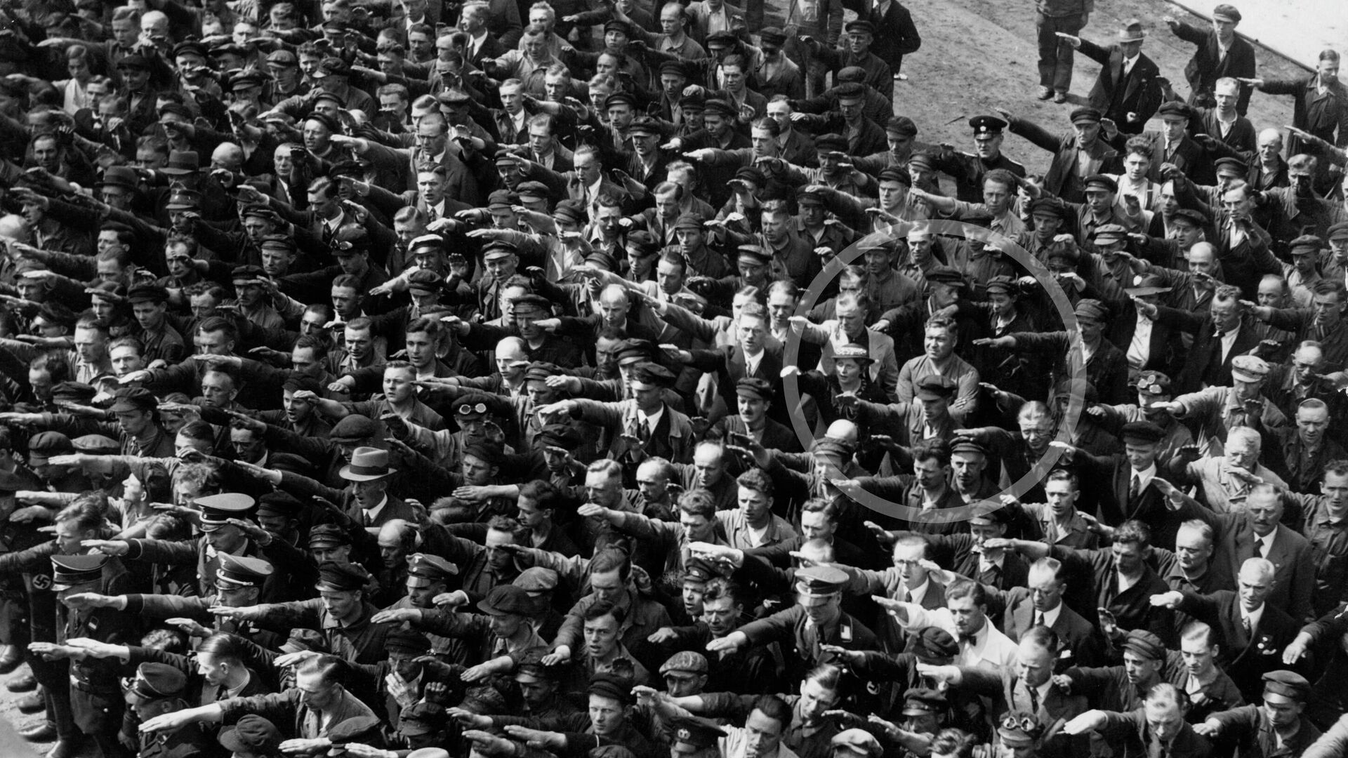 Detalj slavne fotografije na kojoj jedan čovek, za kojeg se veruje da je August Landmeser, odbija da salutira nacističkim pozdravom.
 - Sputnik Srbija, 1920, 27.02.2022