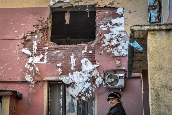 Женщина около дома, поврежденного в результате обстрела в микрорайоне Северный в Волновахе - Sputnik Србија