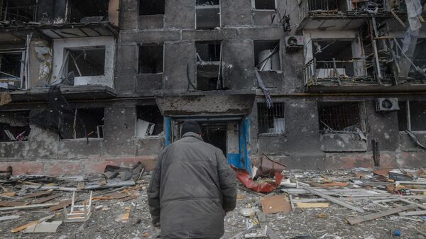 Житель идет к подъезду разрушенного дома на окраине Мариуполя - Sputnik Србија