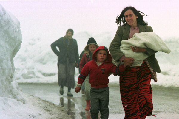 Жена са Косова води своју уплакану децу из Пећи снежним путем ка Црној Гори у среду, 31. марта 1999. Хиљаде избеглица настављају да изливају из зараћене покрајине и кроз националну и регионалну границе. НАТО је у среду одлучио да ескалира своје бомбардовање Југославије пошто је напад достигао једнонедељну границу. - Sputnik Србија