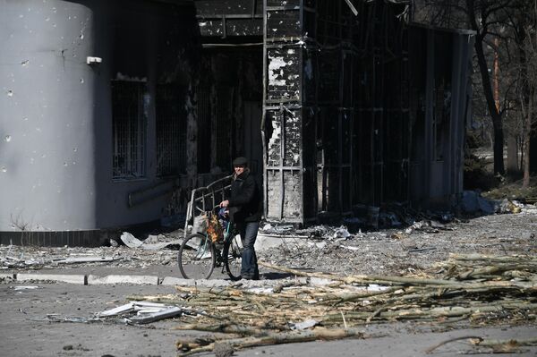 Muškarac sa biciklom u dvorištu stambene zgrade uništene u granatiranju u Marijupolju. - Sputnik Srbija