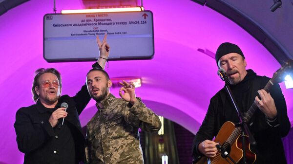 Боно, украјински музичар и војник Тарас Тополиа и Еџ наступају у метроу у Кијеву. - Sputnik Србија