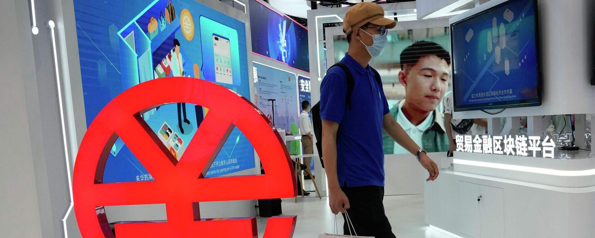 A visitor passes by a logo for the e-CNY, a digital version of the Chinese Yuan, displayed during a trade fair in Beijing, China, Sunday, Sept. 5, 2021 - Sputnik Србија, 1920, 17.12.2022
