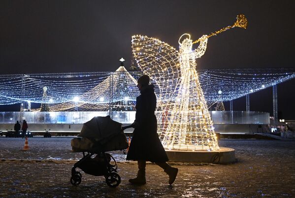 Žena sa kolicima pored figure anđela na Sabornom trgu kod Glavnog hrama Oružanih snaga Rusije na dan otvaranja festivala „Naša zima“. - Sputnik Srbija