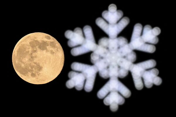 Vučji mesec iza novogodišnje dekoracije u Moskvi 7. januara 2023. - Sputnik Srbija