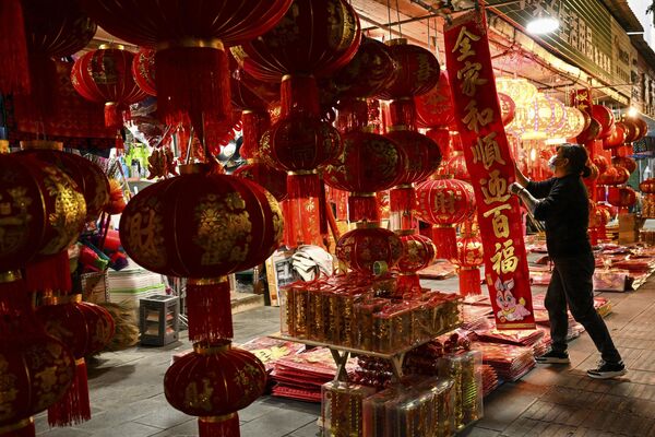 Prodavac organizuje kineske fenjere i druge ukrase za prodaju za predstojeće proslave kineske lunarne Nove godine, u zapadnoj kineskoj provinciji Junan 13. januara 2023. - Sputnik Srbija
