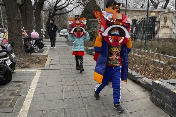 Деца носе картонске маске за игру лавова шетају улицом у Пекингу, петак, 13. јануар 2023. Лавов плес је традиционални део прославе предстојеће лунарне Нове године, којом се званично обележава почетак године Зеца 22. јануара. - Sputnik Србија