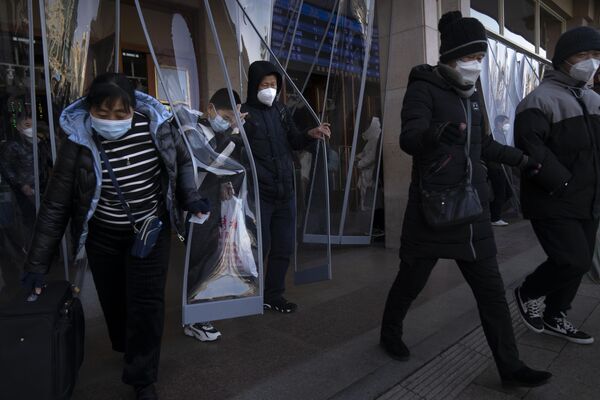 Путници који носе маске излазе са железничке станице у Пекингу у Пекингу, у суботу, 14. јануара 2023. Очекује се да ће милиони Кинеза путовати током празничног периода лунарне Нове године ове године. - Sputnik Србија
