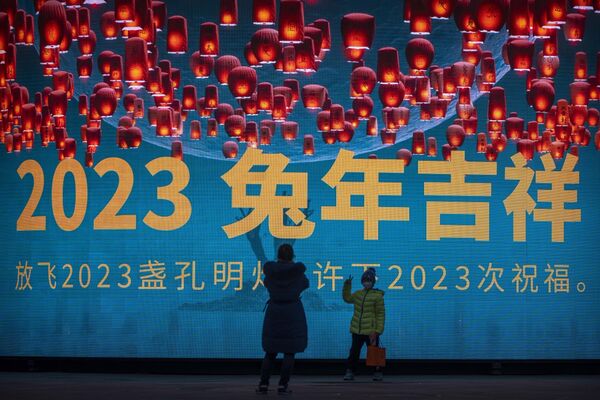 Dečak sa maskom pozira ispred velikog ekrana sa grafičkim ukrasom za predstojeću lunarnu Novu godinu u Pekingu, petak, 13. januara 2023. - Sputnik Srbija