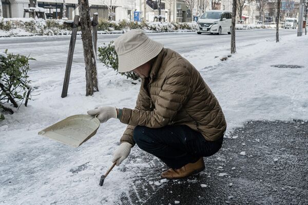 Čovek pokušava da ukloni sneg sa trotoara. (Photo by Fred Mery / AFP) - Sputnik Srbija