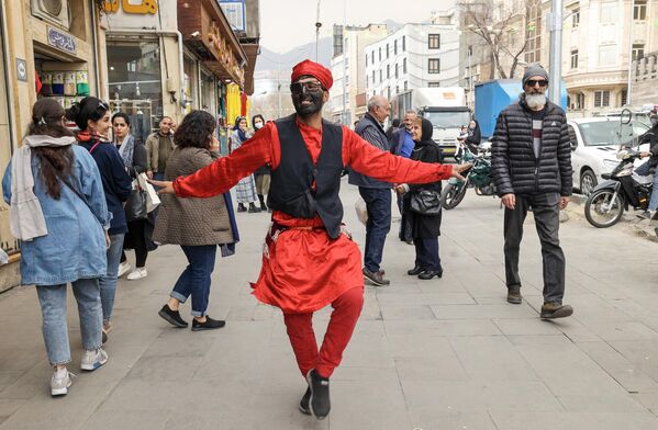 Мушкарац маскиран као фоклорни лик Хаџи Фируз на улицама Техерана. Према предању, Хаџи Фируз се током фестивала Норуз појављује на улицама, обучен у црвено, пева и игра и увесељава људе - Sputnik Србија