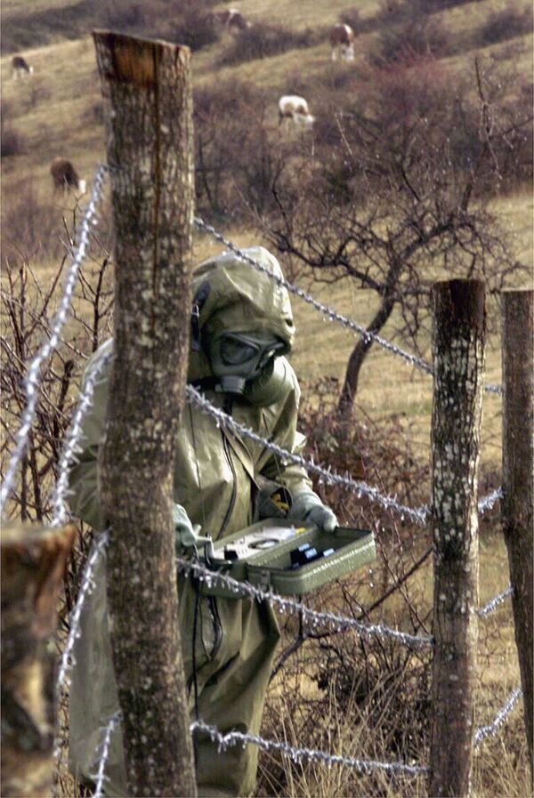 Говеда пасу у близини припадника Војске Југославије који мери радиоактивност у подручју које је гађано током НАТО бомбардовања Југославије, село Рељан код Прешева на југу Србије, 9. јануара 2001.Стручњаци из Београда су саопштили да ће осиромашени уранијум из бомби које су коришћене током НАТО агресије остати у земљишту милијардама година, филтрирајући се у земљу, воду и прелазећи у ланац исхране. - Sputnik Србија
