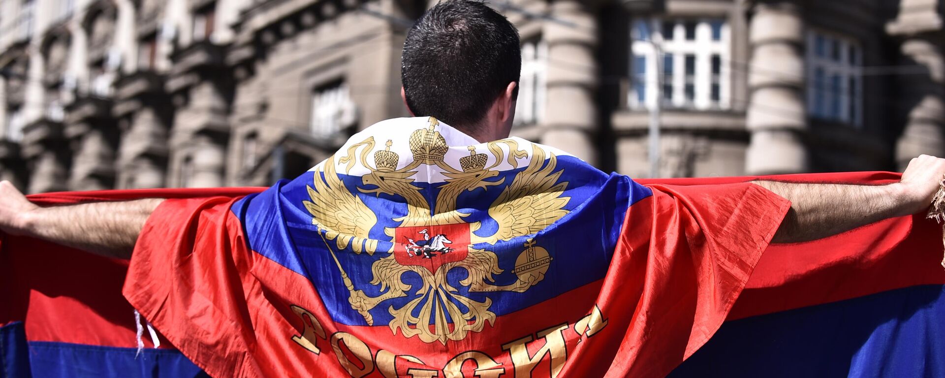 Muškarac ogrnut zastavom Rusije ispred zgrade Vlade Srbije - Sputnik Srbija, 1920, 27.03.2023