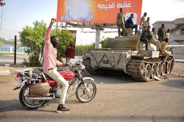Čovek podiže ruku u znak podrške dok prolazi pored vojnika sudanske vojske lojalnih komandantu vojske Abdelu Fatahu al-Burhanu. Vojska je zauzela položaj u gradu Port Sudan na Crvenom moru. - Sputnik Srbija