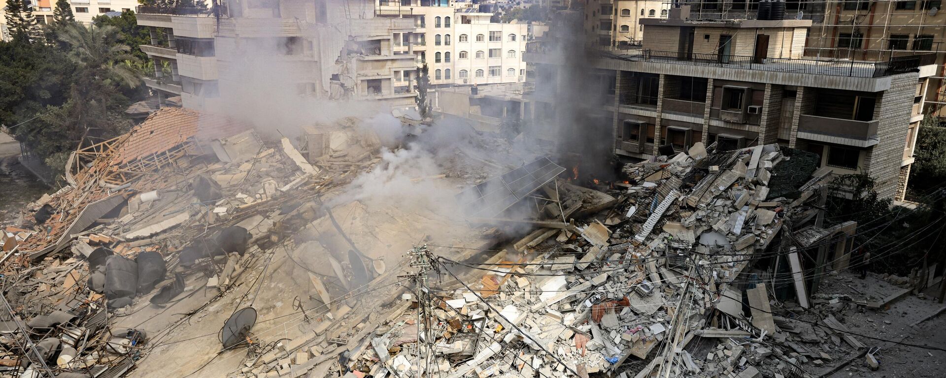 Дым поднимается из-под обломков здания, уничтоженного в результате израильского авиаудара в городе Газа - Sputnik Србија, 1920, 01.11.2023