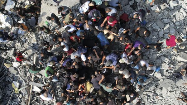 Palestinci okupljeni oko preživelih u izraelskom bombardovanju u Pojasu Gaze - Sputnik Srbija