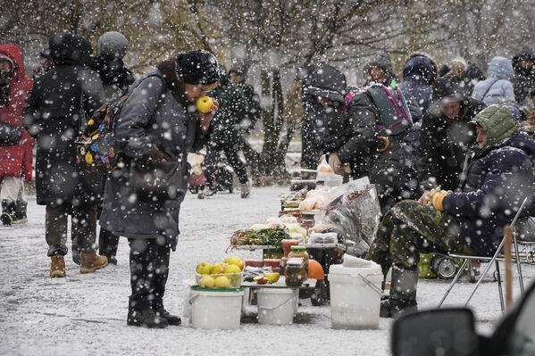 Жена бира јабуке од уличног продавца током снежних падавина у Санкт Петербургу. - Sputnik Србија