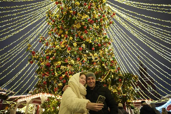 Par se fotografiše na Božićnoj pijaci postavljenoj na trgu Manjež ukrašenom za novogodišnje i božićne svečanosti u blizini zidina Kremlja u Moskvi. - Sputnik Srbija