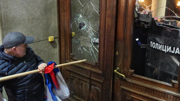 Pristalica koalicije Srbija protiv nasilja (SPN) tokom protesta ispred Skupštine grada ulaza razbija ulazna vrata i prozore na zgradi.  - Sputnik Srbija