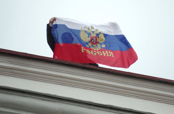 Građanin sa ruskom zastavom na krovu Gradskog veća u Sevastopolju. - Sputnik Srbija