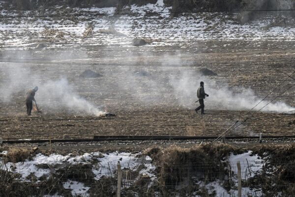 Fotografija snimljena 28. februara 2024. prikazuje ljude iz Severne Koreje koji rade na polju u svojoj zemlji, gledano iz Tumena u severoistočnoj kineskoj provinciji Jilin. - Sputnik Srbija