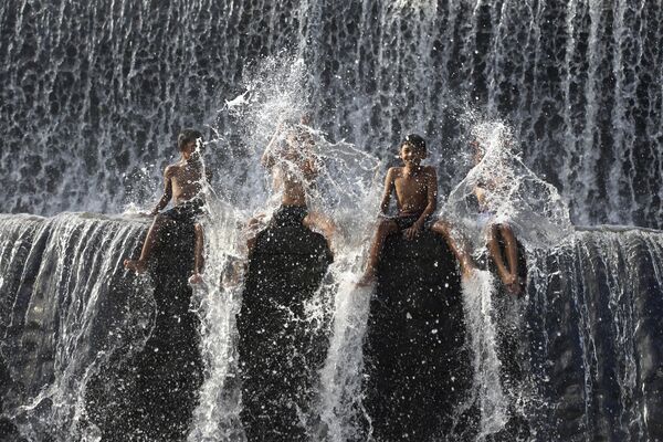 Deca se kupaju na brani reke Unda, uoči Svetskog dana voda, u Klungkungu, Bali, Indonezija, u utorak, 19. marta 2024. Reka Unda, druga po veličini reka na ostrvu Bali, koristi se za razne aktivnosti, poput raftinga, ali i zapoljoprivredno navodnjavanje. - Sputnik Srbija