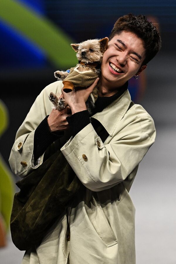 Maneken drži psa dok šeta modnom pistom na modnoj reviji za kućne ljubimce tokom Nedelje mode za kućne ljubimce 2024. u okrugu Jangpu u Šangaju. - Sputnik Srbija
